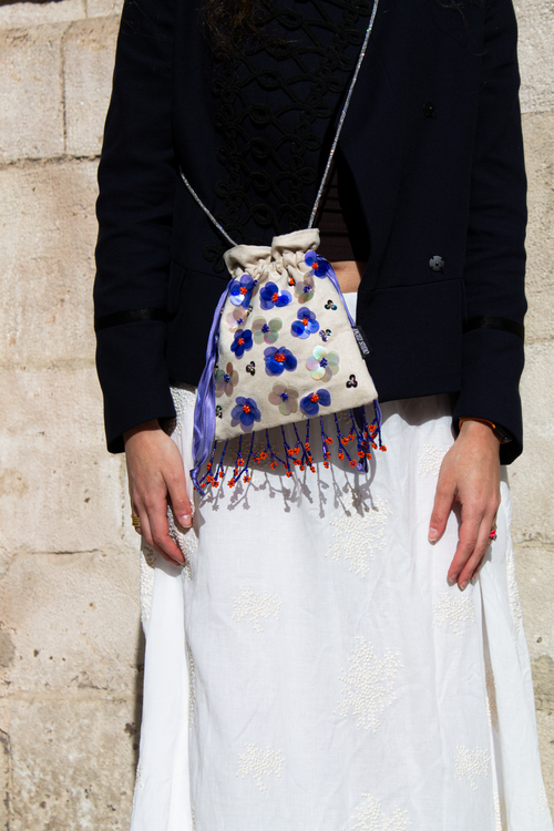 Handcrafted off-white suede drawstring bag with blue sequin flowers & beaded fringe. Internal pocket, 120cm strap, 24×22cm. Perfect for events & everyday glam.