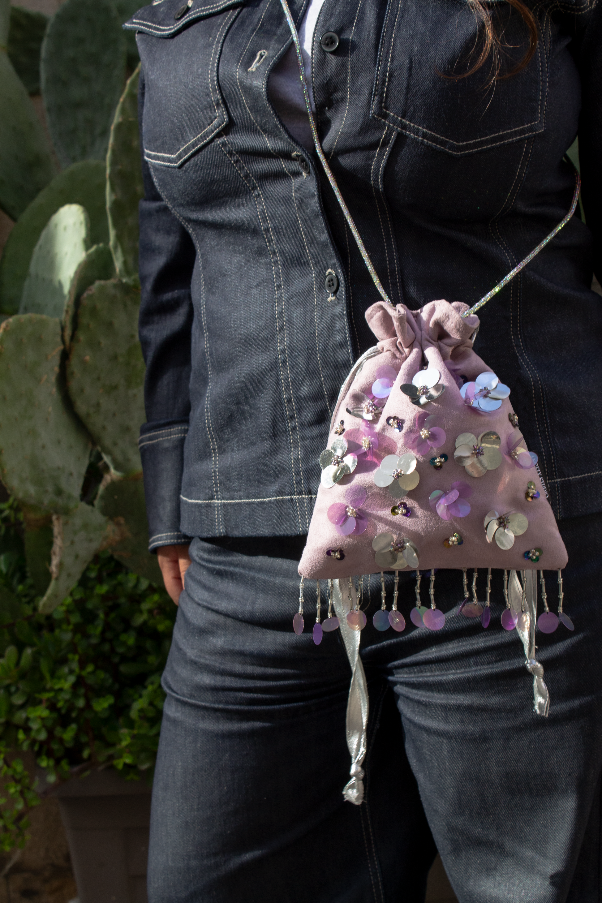 Handcrafted mauve suede drawstring bag with violet and silver sequin flowers & beaded fringe. Internal pocket, 120cm strap, 24×22cm. Perfect for events & everyday glam.