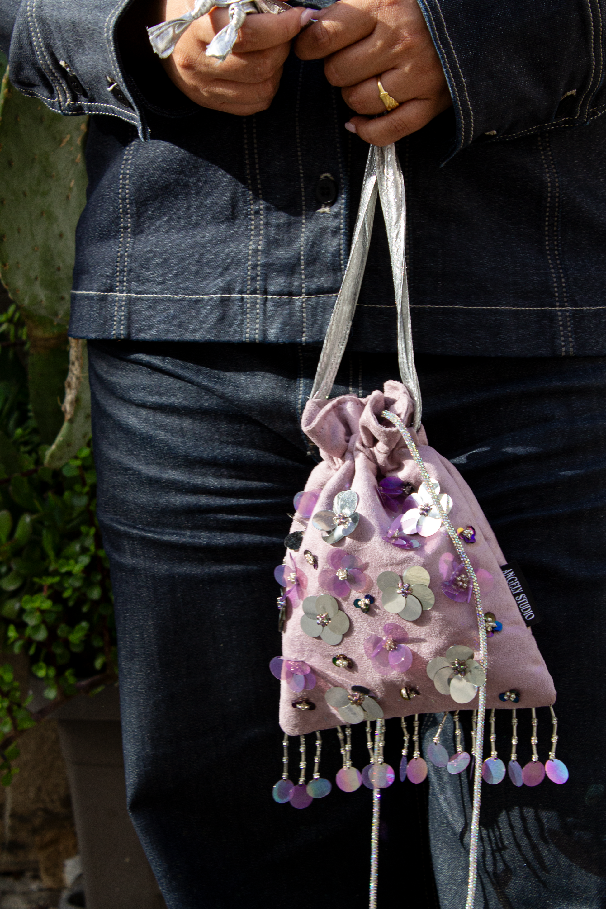 Handcrafted mauve suede drawstring bag with violet and silver sequin flowers & beaded fringe. Internal pocket, 120cm strap, 24×22cm. Perfect for events & everyday glam.